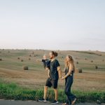 A joyful family walking hand in hand across a picturesque hayfield landscape at sunset.